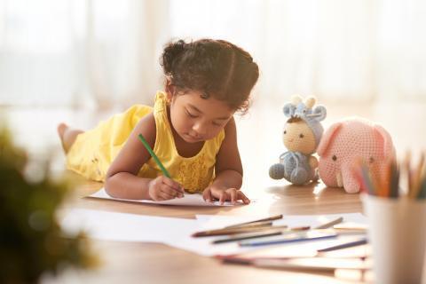 Young child coloring a sheet on the floor