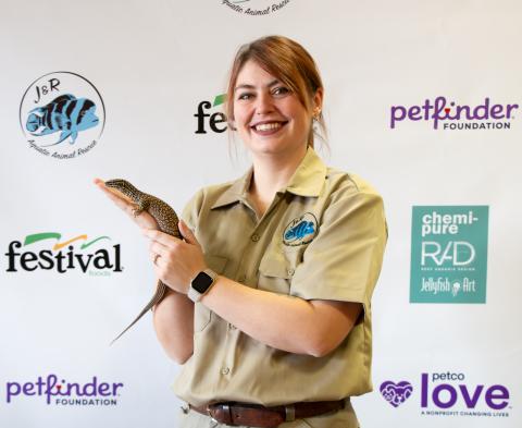 A woman is holding a lizard in her hand.