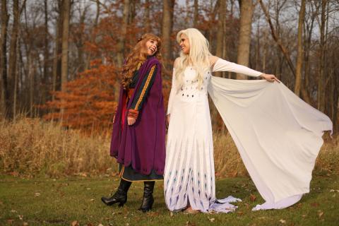 A princess with red hair and a princess in all white pose together